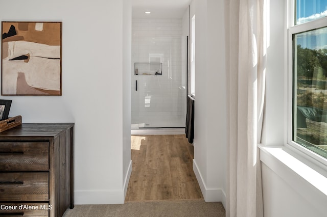 hall with a healthy amount of sunlight, light hardwood / wood-style flooring, and a baseboard radiator