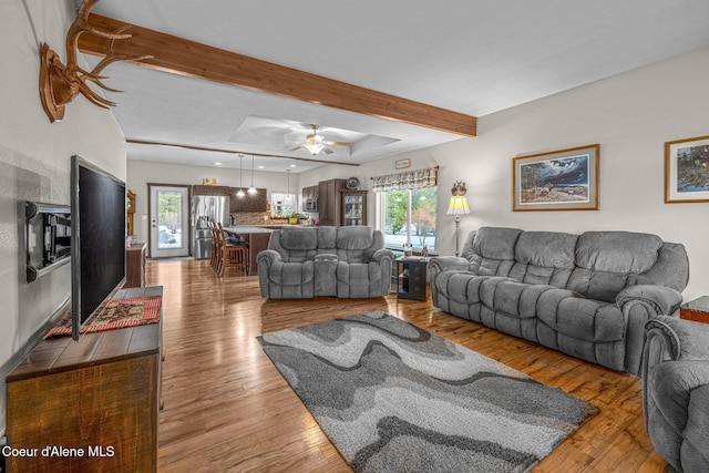 living room with beamed ceiling, hardwood / wood-style floors, and ceiling fan