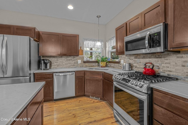 kitchen with tasteful backsplash, appliances with stainless steel finishes, sink, and decorative light fixtures