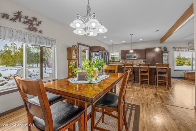 dining area with a healthy amount of sunlight, a chandelier, beam ceiling, and light hardwood / wood-style flooring