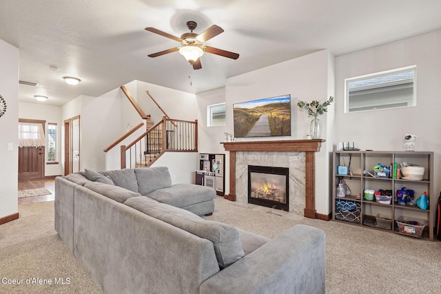 living room featuring ceiling fan, light colored carpet, and a fireplace