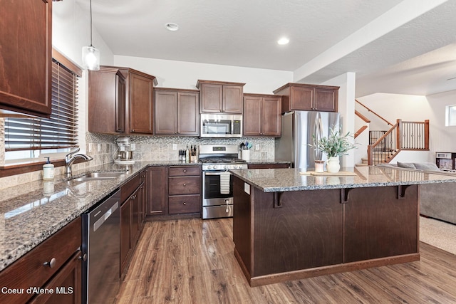 kitchen featuring a breakfast bar, hanging light fixtures, appliances with stainless steel finishes, and sink