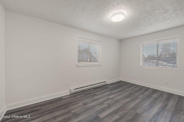 empty room featuring dark hardwood / wood-style flooring, a baseboard radiator, a textured ceiling, and plenty of natural light