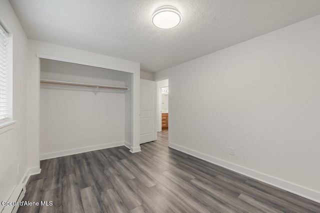 unfurnished bedroom featuring dark wood-type flooring, a baseboard radiator, a closet, and a textured ceiling