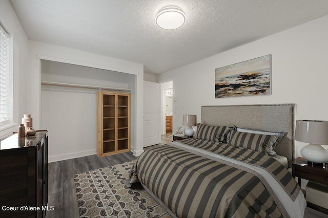 bedroom featuring ensuite bathroom, dark wood-type flooring, a textured ceiling, and a closet