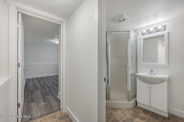 bathroom with hardwood / wood-style floors, vanity, a shower with door, and a textured ceiling