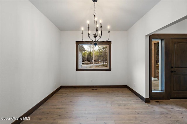 unfurnished dining area with light hardwood / wood-style floors and a notable chandelier