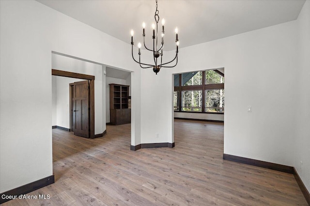 unfurnished dining area featuring a chandelier and hardwood / wood-style flooring