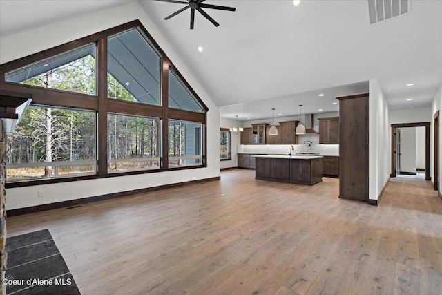 unfurnished living room featuring ceiling fan, high vaulted ceiling, a wealth of natural light, and light hardwood / wood-style flooring