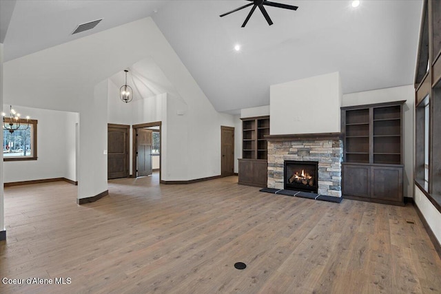 unfurnished living room featuring high vaulted ceiling, light wood-type flooring, a fireplace, and ceiling fan with notable chandelier