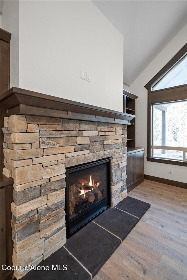 room details with hardwood / wood-style floors and a stone fireplace