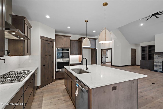 kitchen featuring tasteful backsplash, pendant lighting, sink, an island with sink, and stainless steel appliances