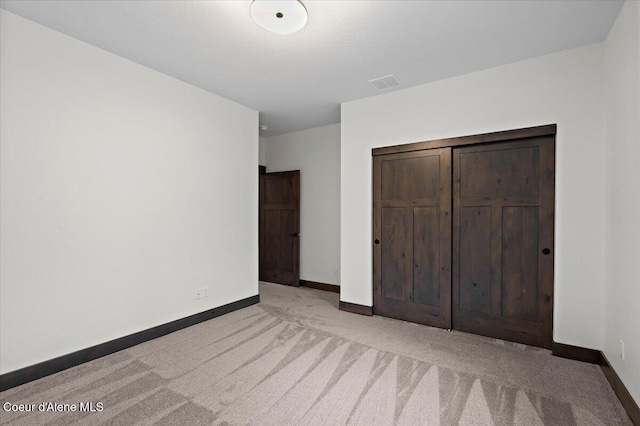 unfurnished bedroom featuring light carpet and a closet