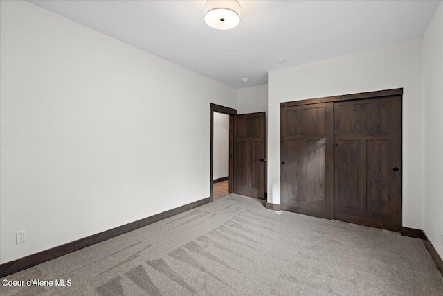 unfurnished bedroom with a closet and light colored carpet