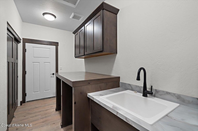 laundry area featuring light hardwood / wood-style floors, sink, and a textured ceiling