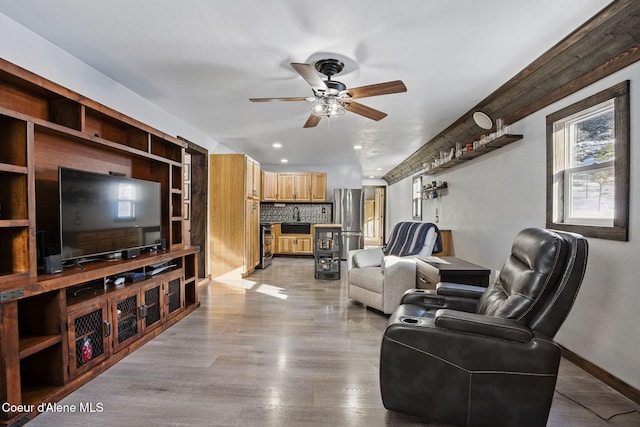 living room featuring sink, light hardwood / wood-style floors, and ceiling fan