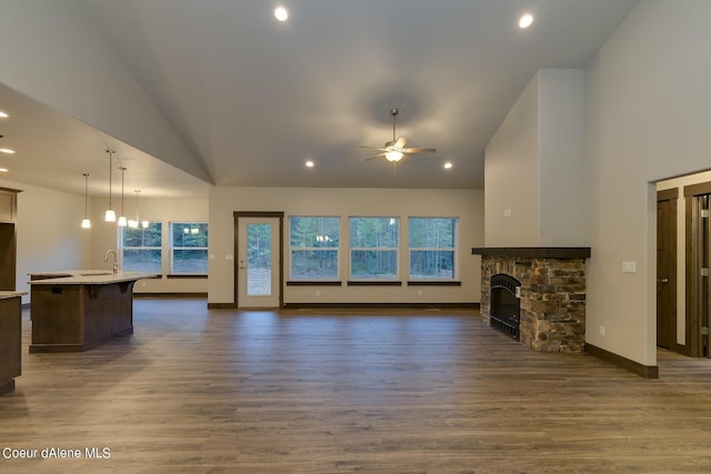 unfurnished living room featuring dark wood-type flooring, a fireplace, and high vaulted ceiling