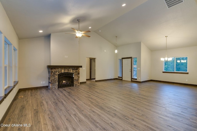 unfurnished living room featuring a fireplace, dark wood-type flooring, ceiling fan with notable chandelier, and high vaulted ceiling