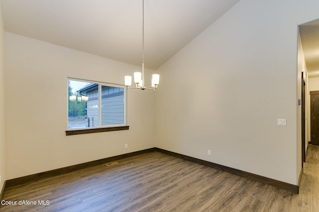 spare room featuring dark wood-type flooring, a notable chandelier, and vaulted ceiling