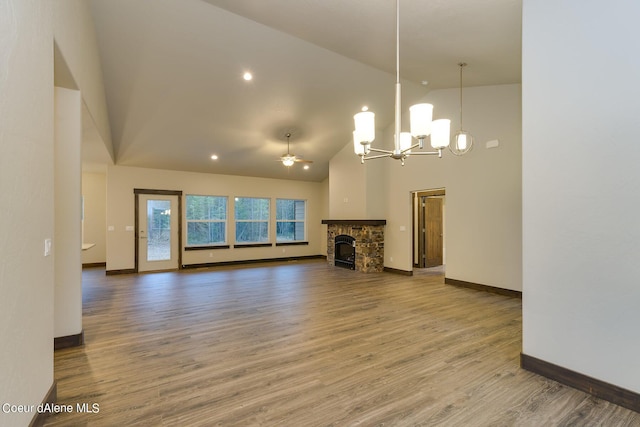 unfurnished living room featuring high vaulted ceiling, a fireplace, wood-type flooring, and ceiling fan with notable chandelier