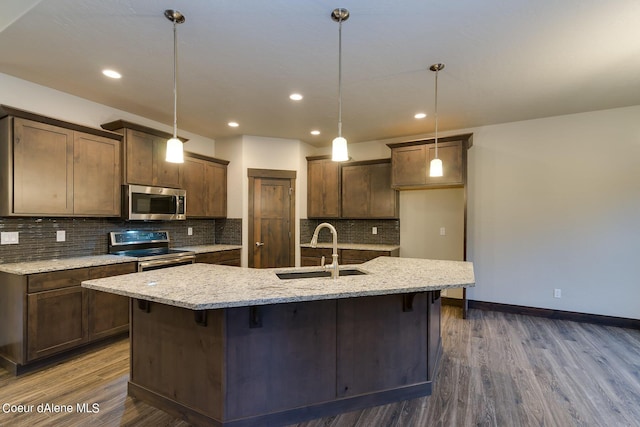 kitchen featuring hanging light fixtures, a kitchen island with sink, sink, and stainless steel appliances