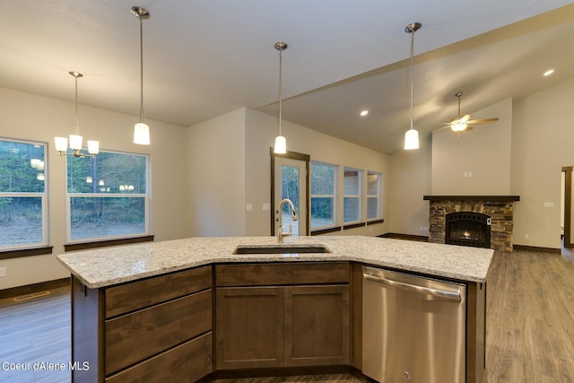 kitchen featuring lofted ceiling, a fireplace, hardwood / wood-style floors, stainless steel dishwasher, and sink