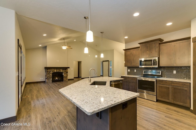 kitchen featuring decorative light fixtures, tasteful backsplash, sink, a kitchen island with sink, and appliances with stainless steel finishes