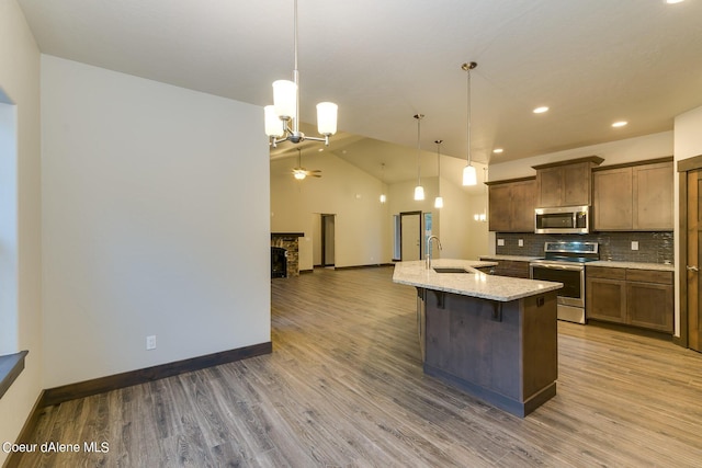 kitchen with decorative light fixtures, appliances with stainless steel finishes, a breakfast bar area, and an island with sink