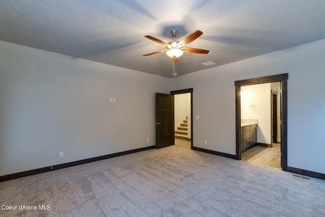 unfurnished bedroom featuring ceiling fan, light carpet, and connected bathroom