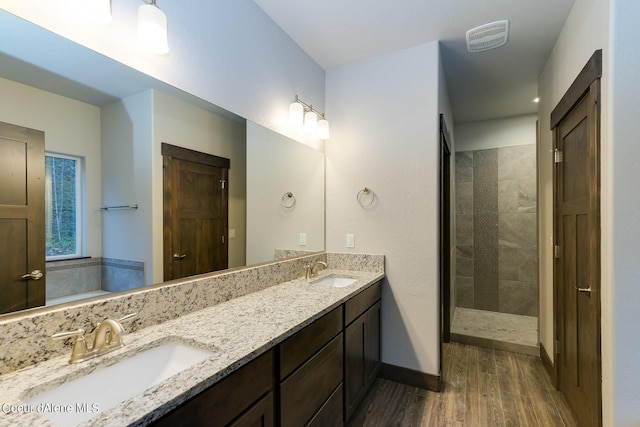 bathroom with vanity, wood-type flooring, and tiled shower