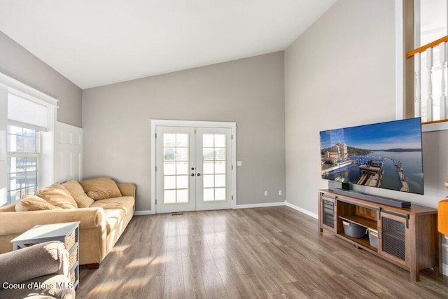 living room featuring wood-type flooring, high vaulted ceiling, and french doors