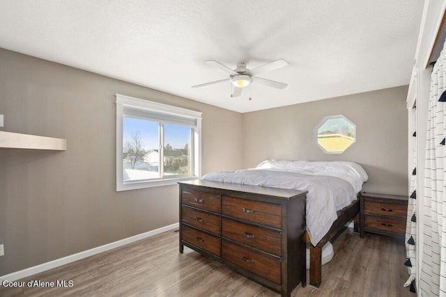 bedroom featuring ceiling fan, hardwood / wood-style floors, and a textured ceiling