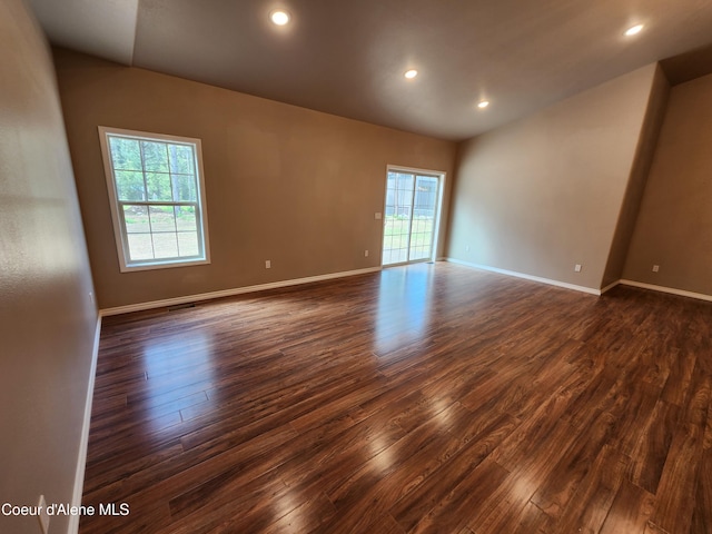 empty room with a wealth of natural light and dark hardwood / wood-style floors