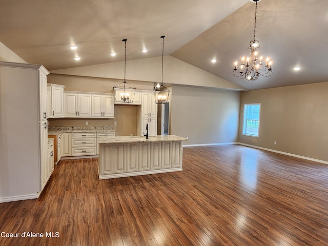 kitchen featuring decorative light fixtures, a kitchen island with sink, dark hardwood / wood-style floors, and light stone counters