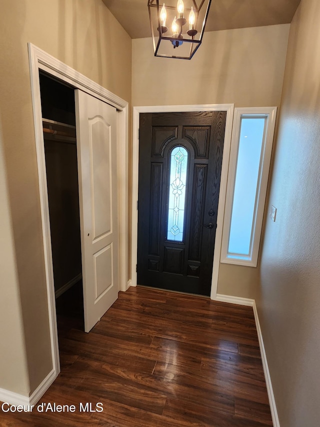 entryway with dark wood-type flooring and a notable chandelier