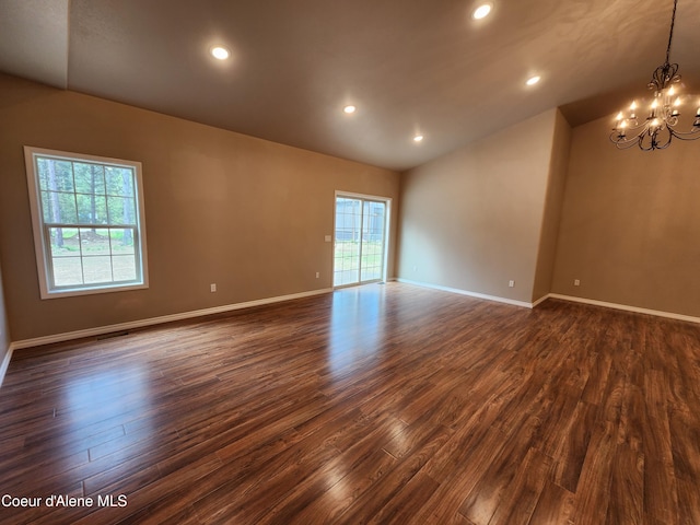 spare room with dark hardwood / wood-style flooring, lofted ceiling, and a notable chandelier