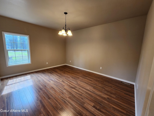 spare room featuring dark hardwood / wood-style flooring and a notable chandelier