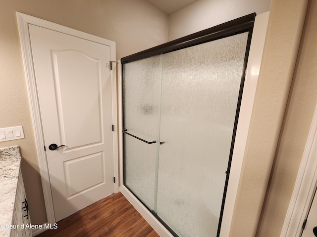 bathroom with a shower with shower door, hardwood / wood-style floors, and vanity