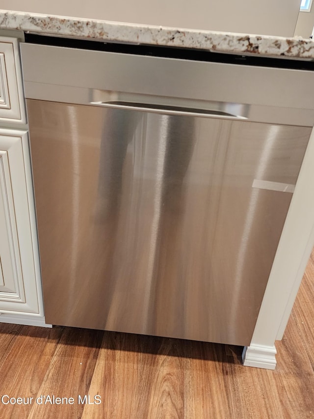 details with stainless steel dishwasher and light hardwood / wood-style flooring