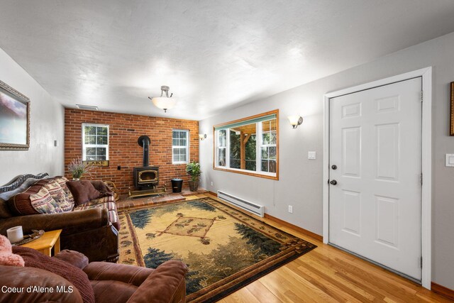 19503 E Hayden Lake Rd, Hayden, ID 83835 - living area with visible vents, light wood-style flooring, baseboards, baseboard heating, and a wood stove
