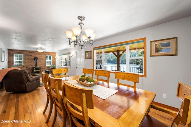 19503 E Hayden Lake Rd, Hayden, ID 83835 - dining space featuring baseboards, a wood stove, an inviting chandelier, and light wood finished floors
