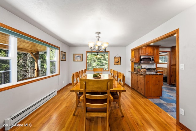 19503 E Hayden Lake Rd, Hayden, ID 83835 - dining area with baseboards, light wood-style flooring, a baseboard heating unit, and an inviting chandelier