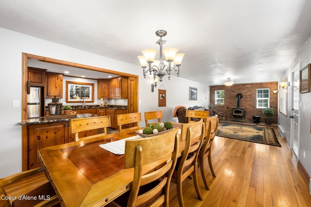 19503 E Hayden Lake Rd, Hayden, ID 83835 - dining room featuring baseboards, light wood-style floors, a wood stove, and an inviting chandelier