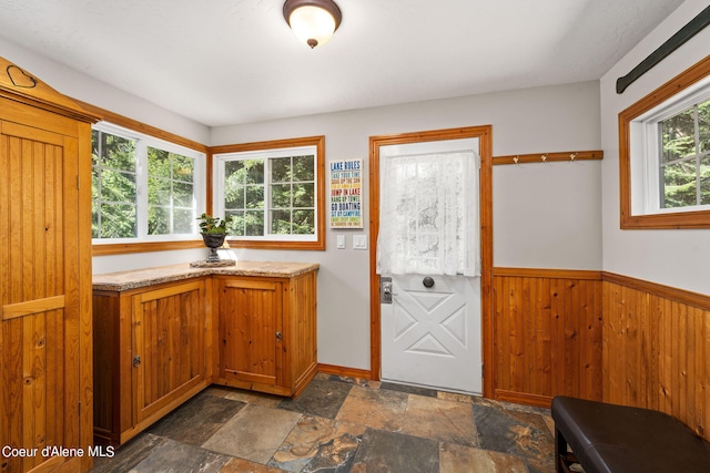 19503 E Hayden Lake Rd, Hayden, ID 83835 - interior space featuring a wainscoted wall, stone finish flooring, brown cabinetry, and wooden walls
