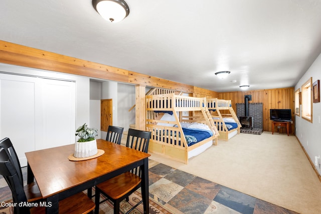 19503 E Hayden Lake Rd, Hayden, ID 83835 - carpeted dining space featuring stone finish floor, wood walls, and a wood stove