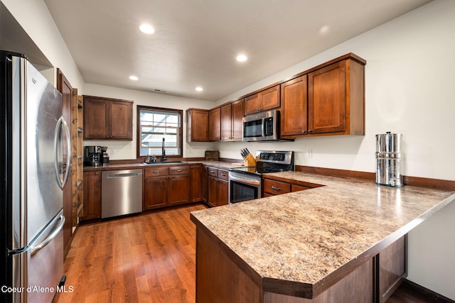 kitchen featuring dark hardwood / wood-style flooring, sink, kitchen peninsula, and appliances with stainless steel finishes