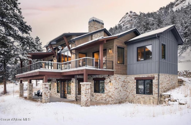 snow covered rear of property featuring a balcony