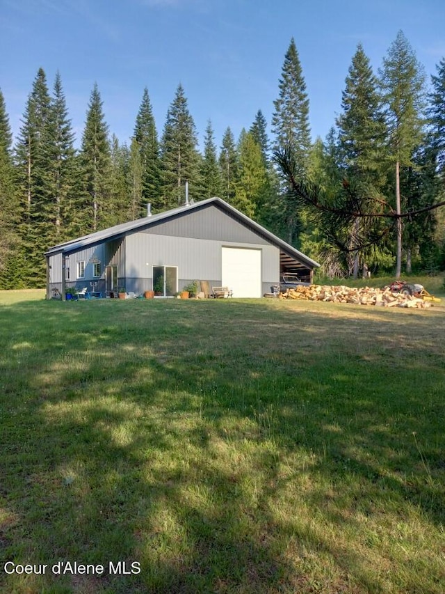 view of side of home featuring a garage, a lawn, and an outdoor structure