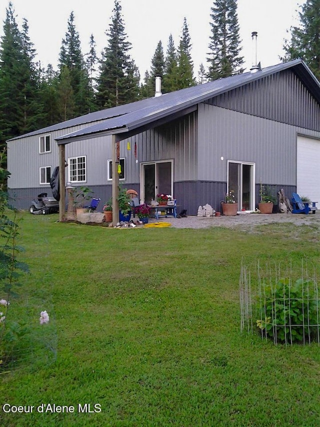 rear view of property featuring a garage and a yard