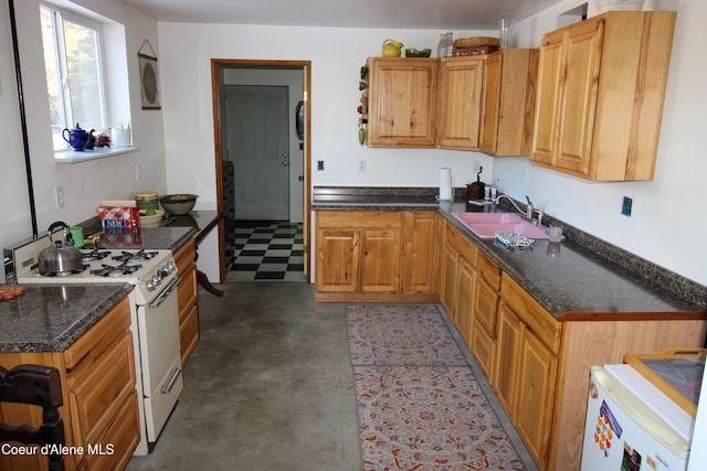 kitchen with white gas range, sink, and dark stone counters